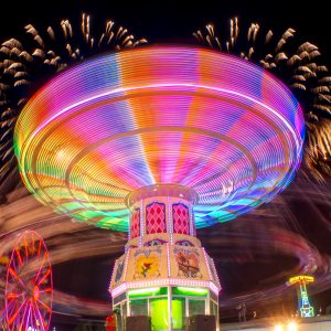 Feria de Leon Guanajuato - luces de Juego mecánico girando y fuegos artificiales al fondo